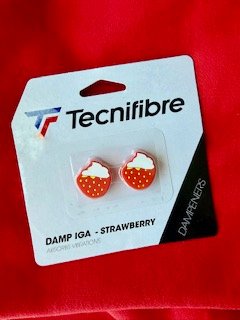 A red, strawberry designed Technifibre tennis vibration dampener purchased as a tournament souvenir.